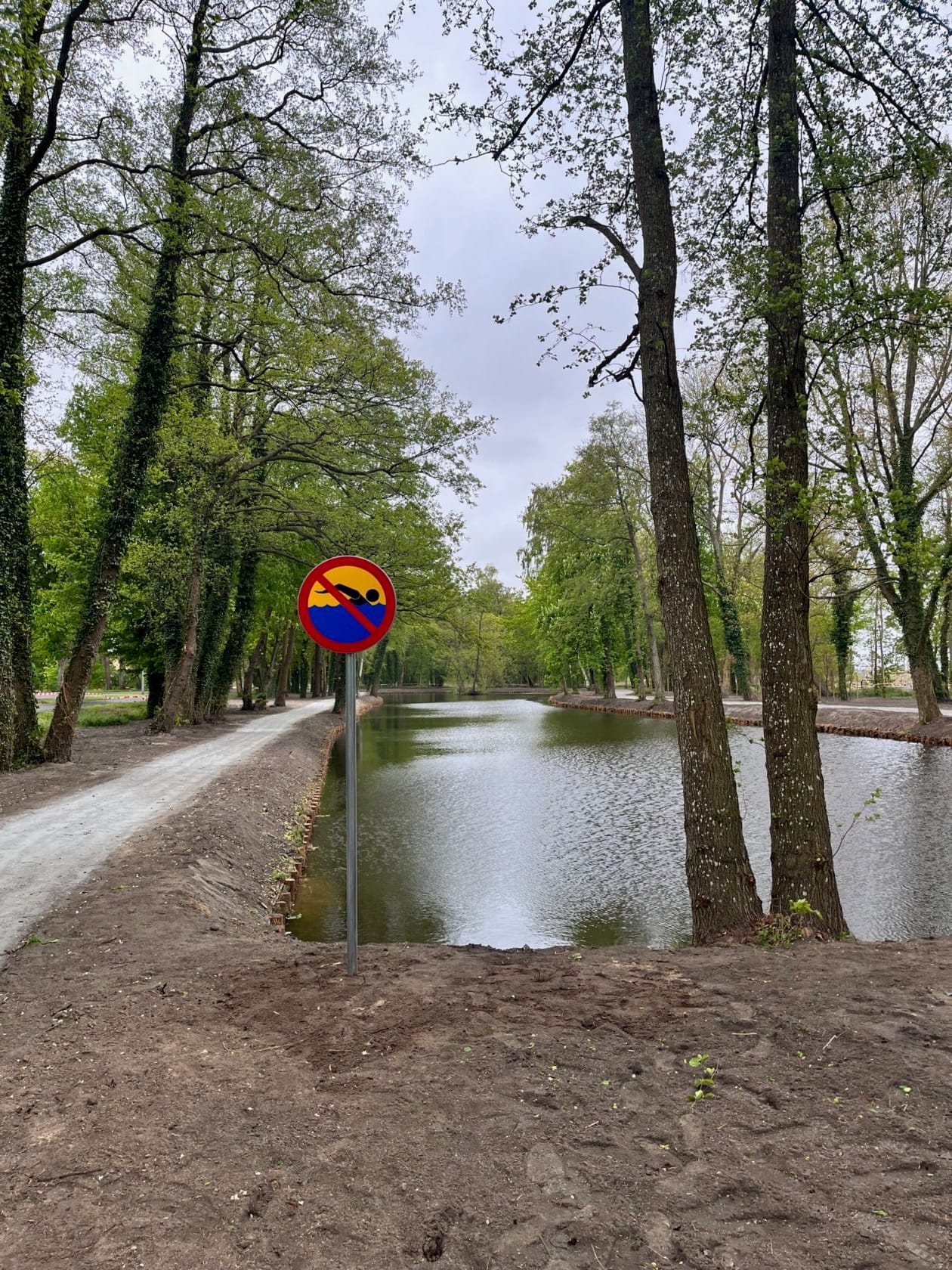 Zakaz wjazdu przed parkiem i stawem otoczonym drzewami