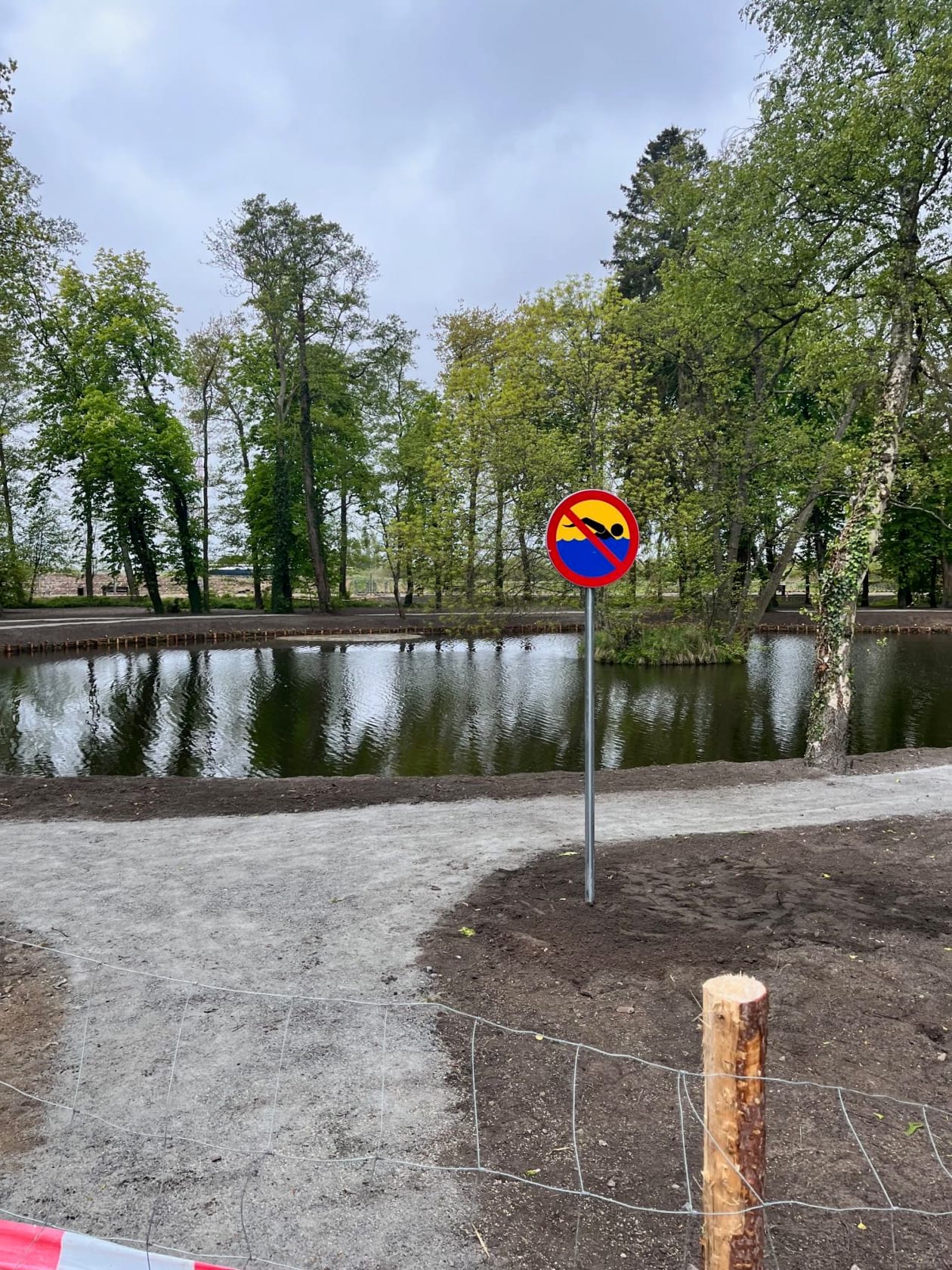 Znak zakazu kąpieli obok stawu w parku