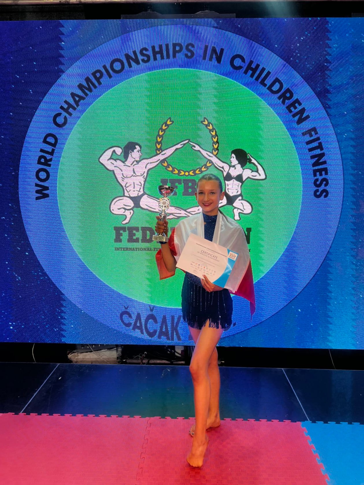 Młoda zawodniczka z trofeum na mistrzostwach fitness dzieci