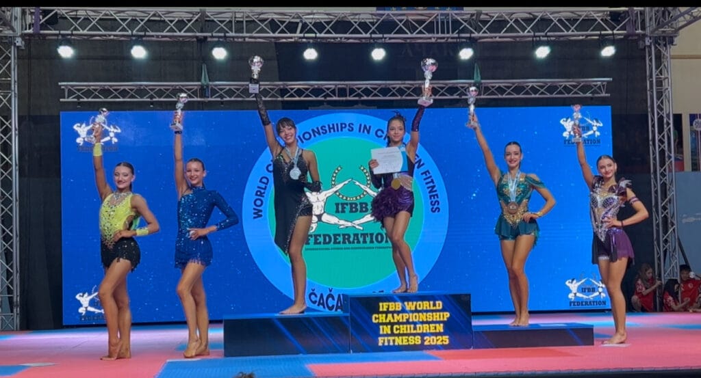 Młode gimnastyczki z trofeami na scenie mistrzostw IFBB 2025