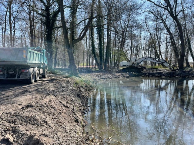 Budowa przy rzece, maszyny budowlane i drzewa