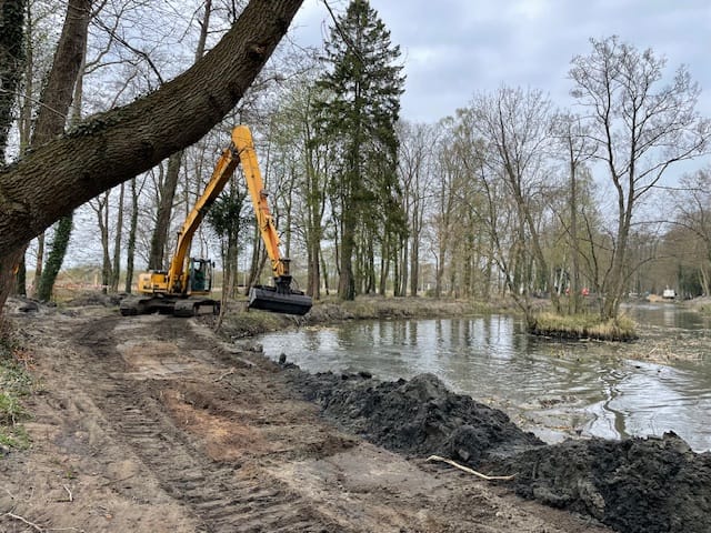 Koparka przy pracy nad wykopem nad brzegiem rzeki