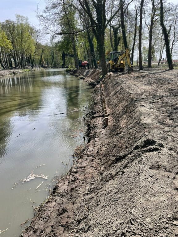 Prace remontowe nad brzegiem rzeki, koparki, drzewa