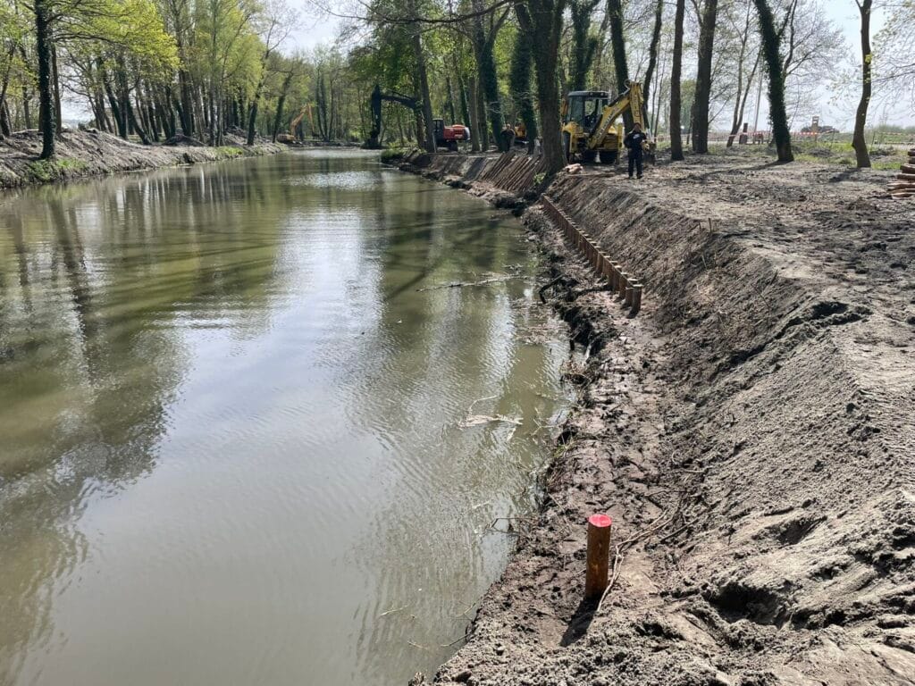 Prace ziemne przy rzece, koparki i robotnicy