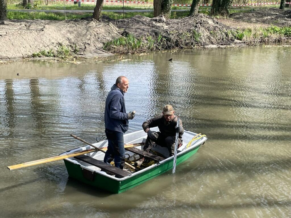 Dwóch mężczyzn wiosłuje na łodzi na rzece