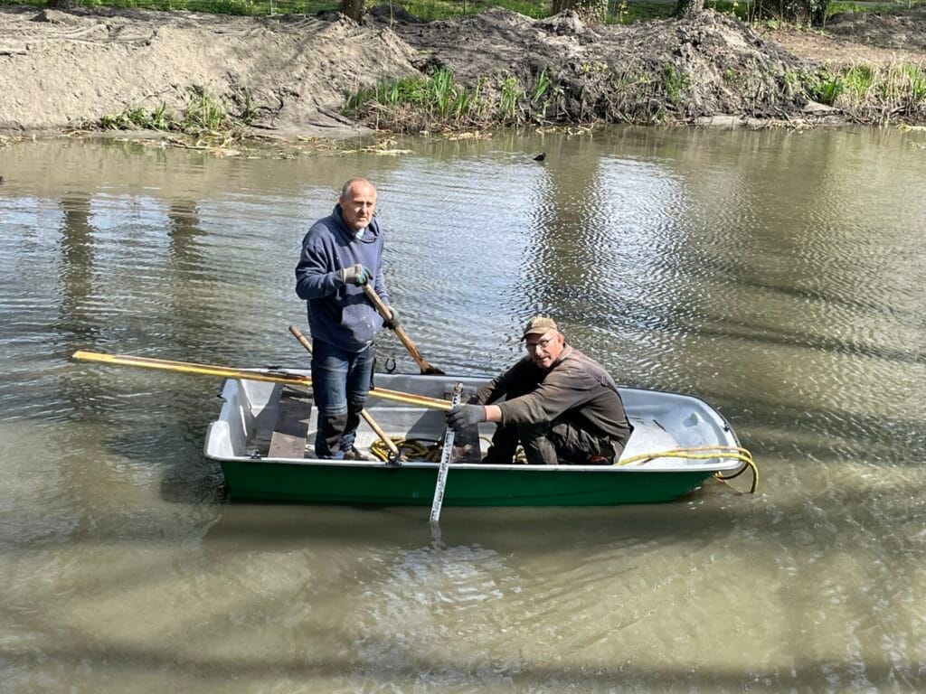 Dwóch mężczyzn w łódce wiosłujących na rzece
