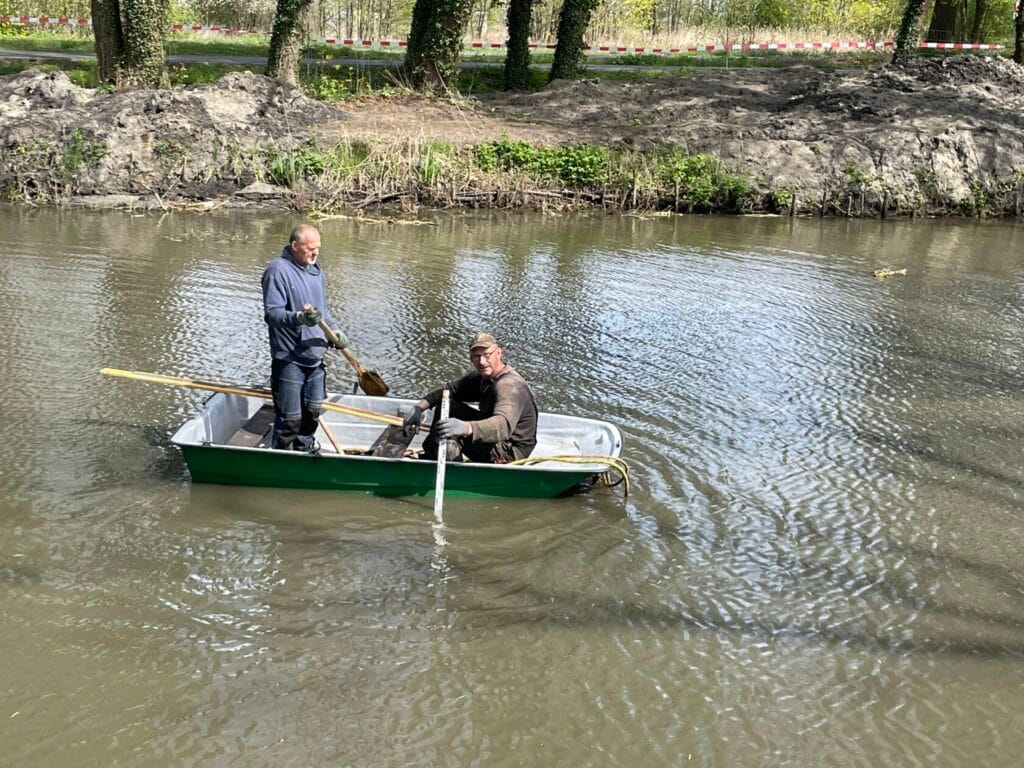 Dwóch mężczyzn w łódce na rzece, wiosłują.
