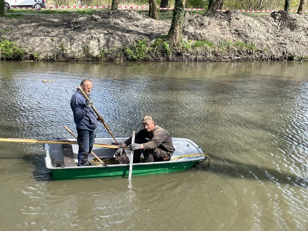 Dwaj mężczyźni na łódce, pracują nad rzeką