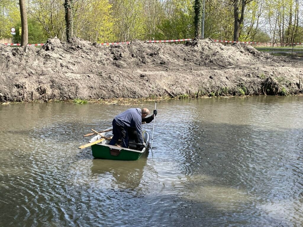 Mężczyzna w łódce łowi ryby na rzece.