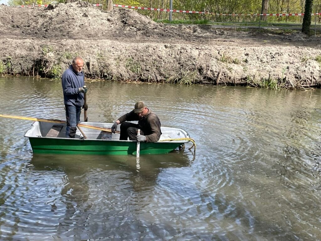 Dwóch mężczyzn na łódce na rzece, pomiar głębokości
