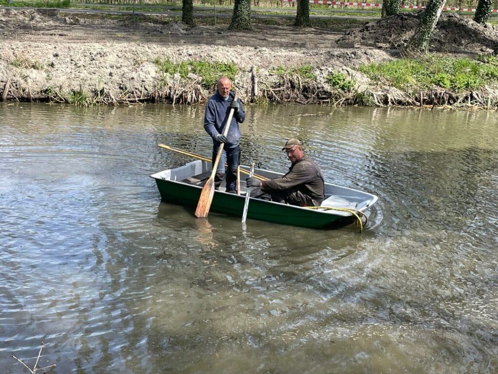 Dwóch mężczyzn w łódce wiosłującej na rzece