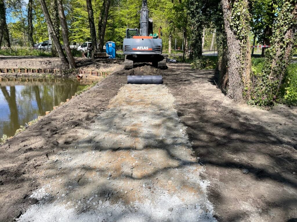 Prace drogowe przy użyciu koparki obok stawu