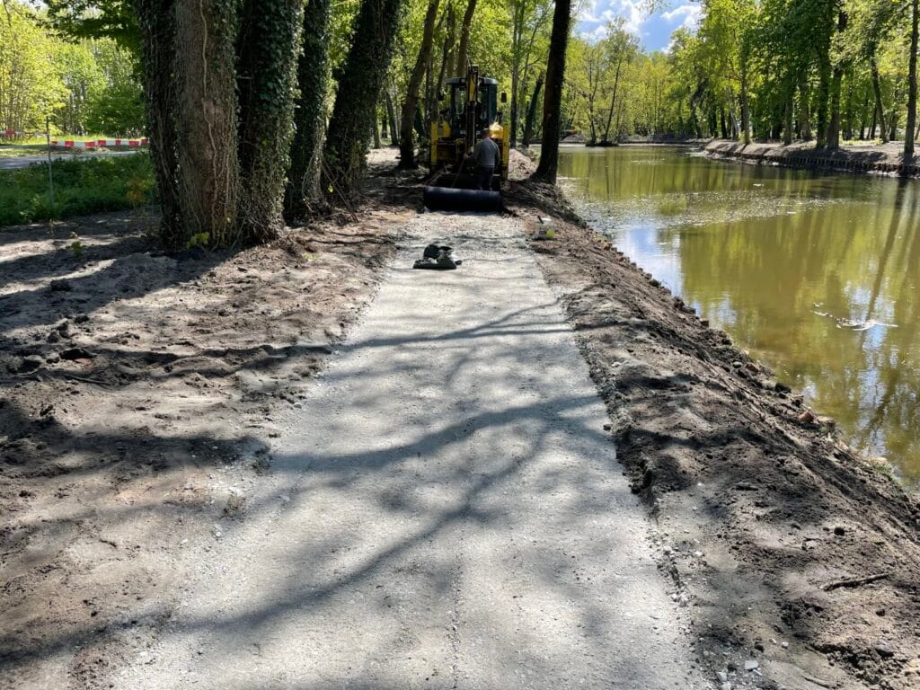Remont ścieżki nad brzegiem rzeki z koparką