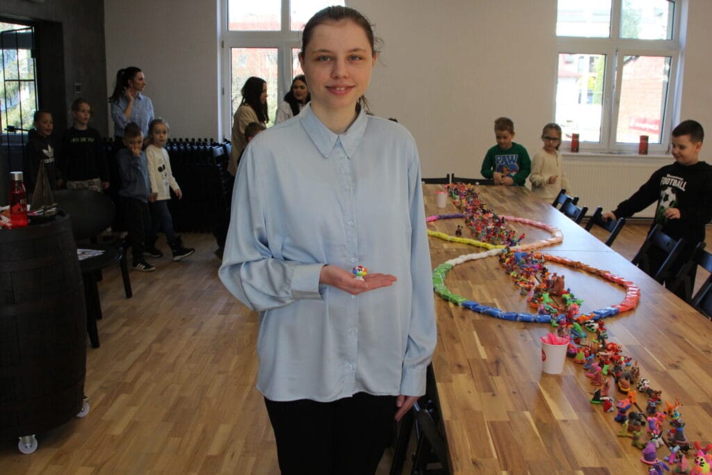 Dziewczyna pokazuje rękodzieło z plasteliny w sali