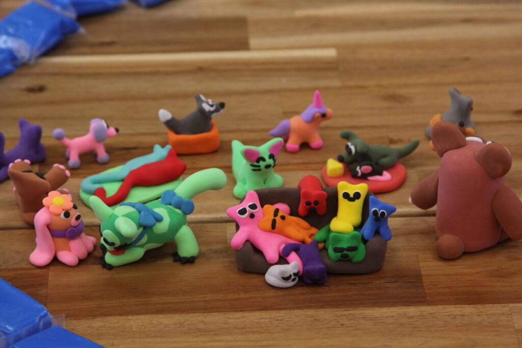 Kolorowe figurki z plasteliny na drewnianej podłodze.