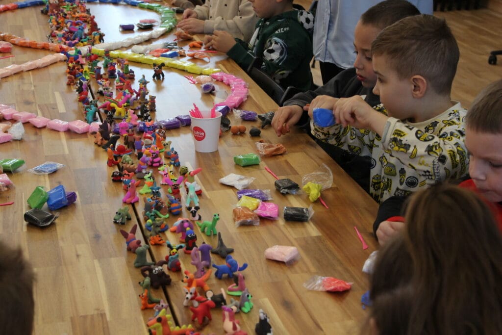 Dzieci modelujące kreatywne figurki z plasteliny przy stole