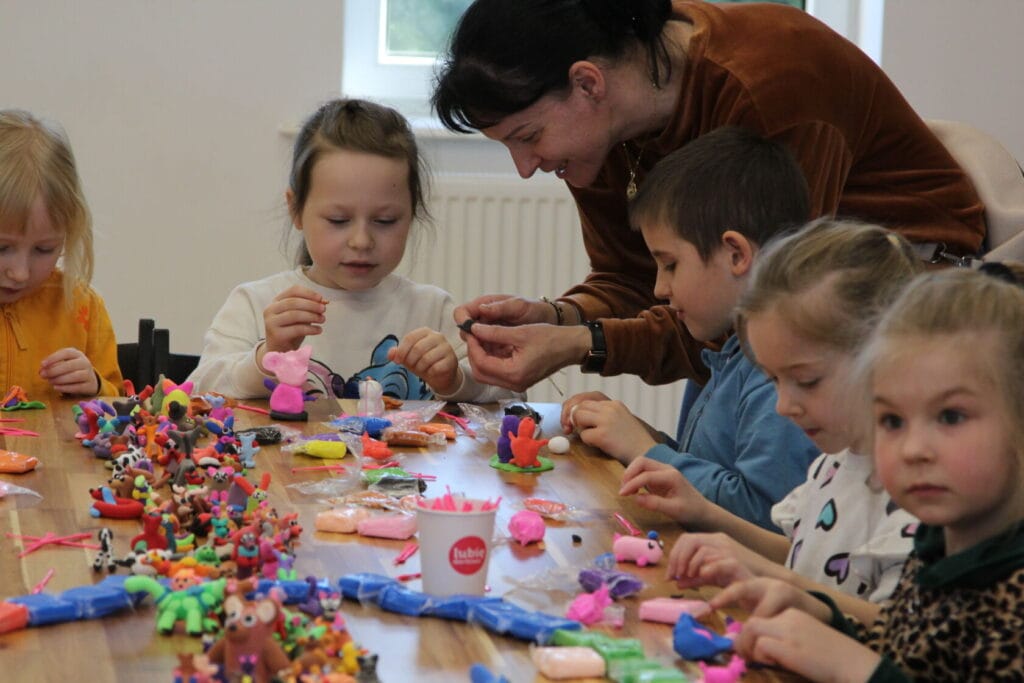 Dzieci i kobieta modelujące figury z plasteliny
