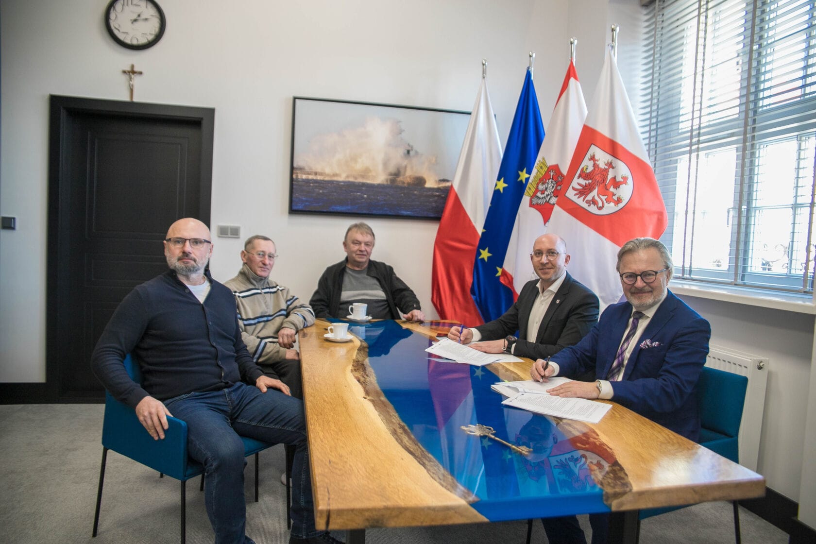 Mężczyźni dyskutują przy stole z flagami w tle