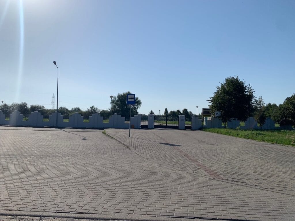Pusty parking z kostki brukowej, drzewa, ogrodzenie