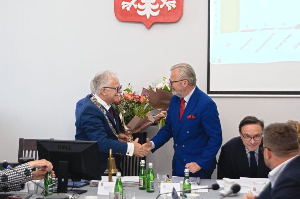 Dwaj starsi mężczyźni uścisk dłoni, wręczają kwiaty na konferencji.