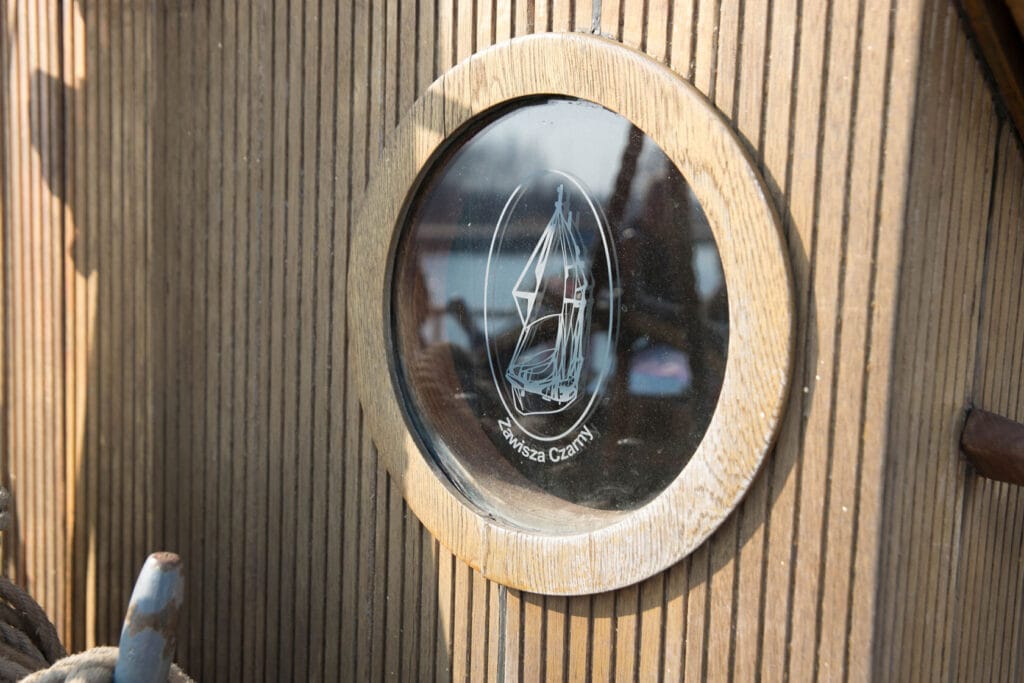 Rzeźbiona drewniana tablica z okrągłym oknem i żaglowcem