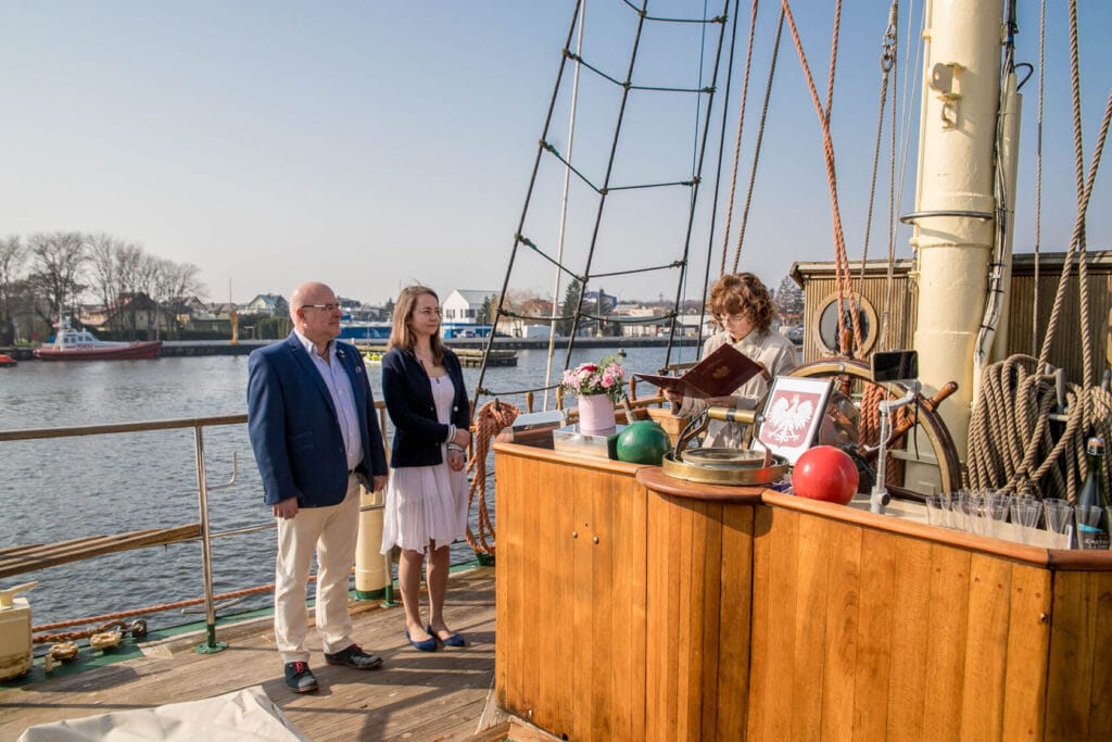 Ślubna ceremonia na pokładzie żaglowca, port w tle