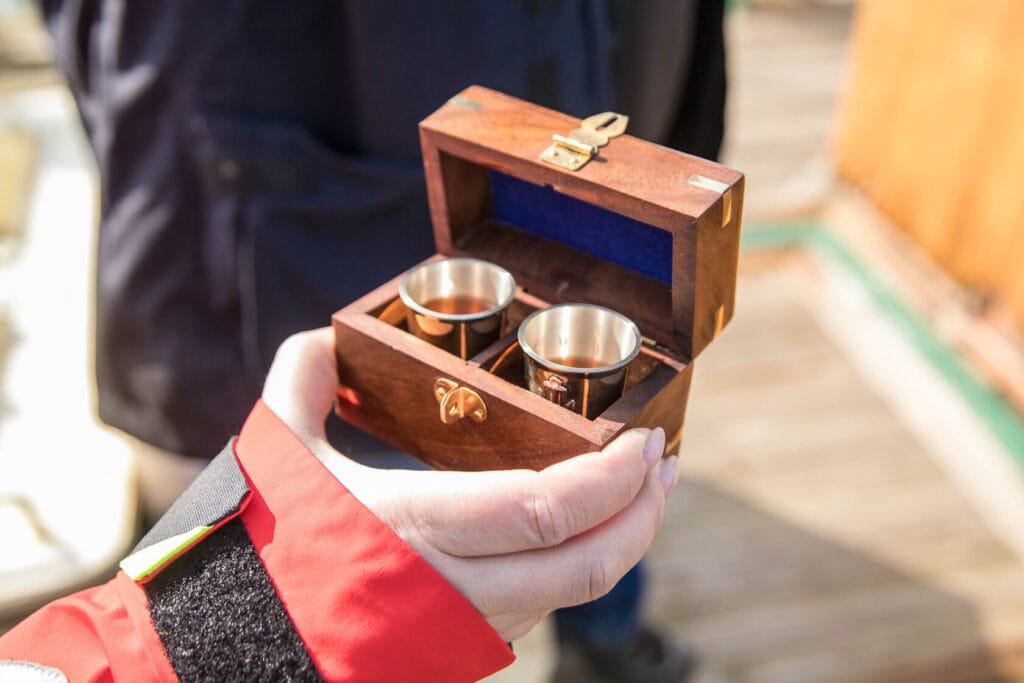 Osoba trzyma drewniane pudełko z metalowymi kubkami