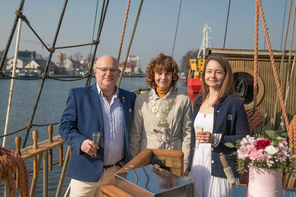 Trzy osoby toastują szampanem na żaglowcu