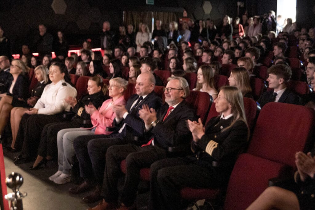 Tłum ludzi na wydarzeniu w kinie oklaskuje