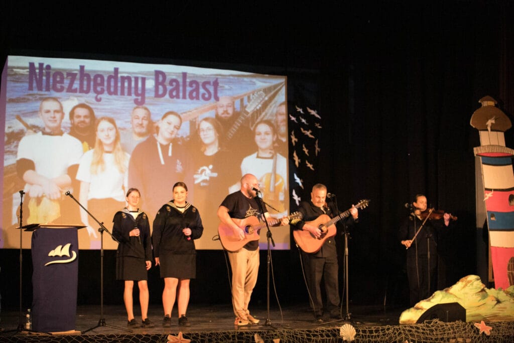 Zespół muzyczny wykonuje przed bannerem 'Niezbedny Balast'