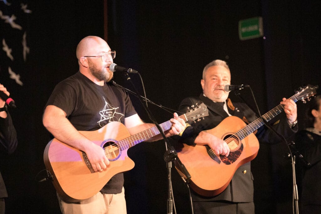 Mężczyźni grają na gitarach i śpiewają na scenie