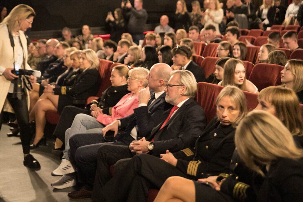 Ludzie siedzą na widowni teatru podczas wydarzenia.