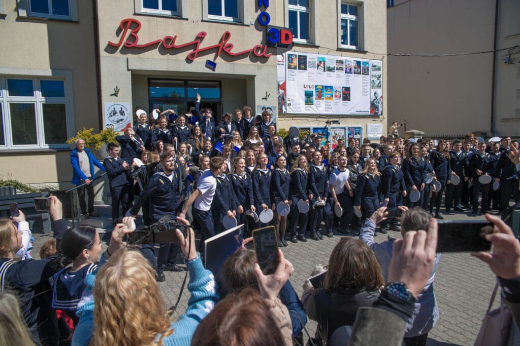 Młodzież w mundurkach świętuje przed kinem.