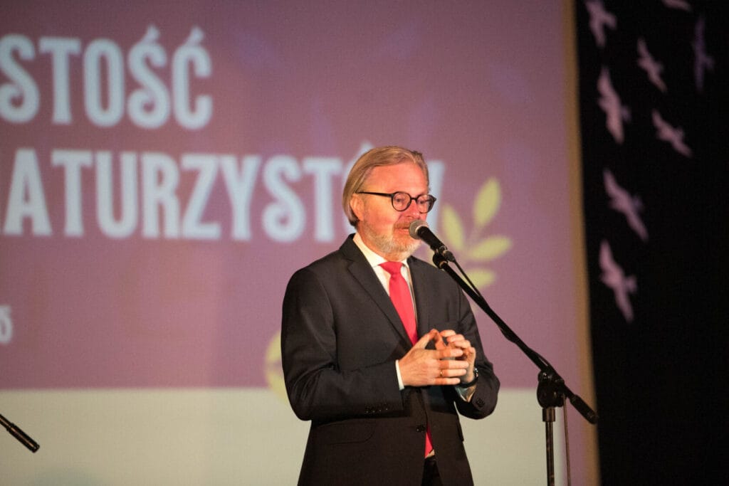 Starszy mężczyzna przemawia na scenie podczas wydarzenia