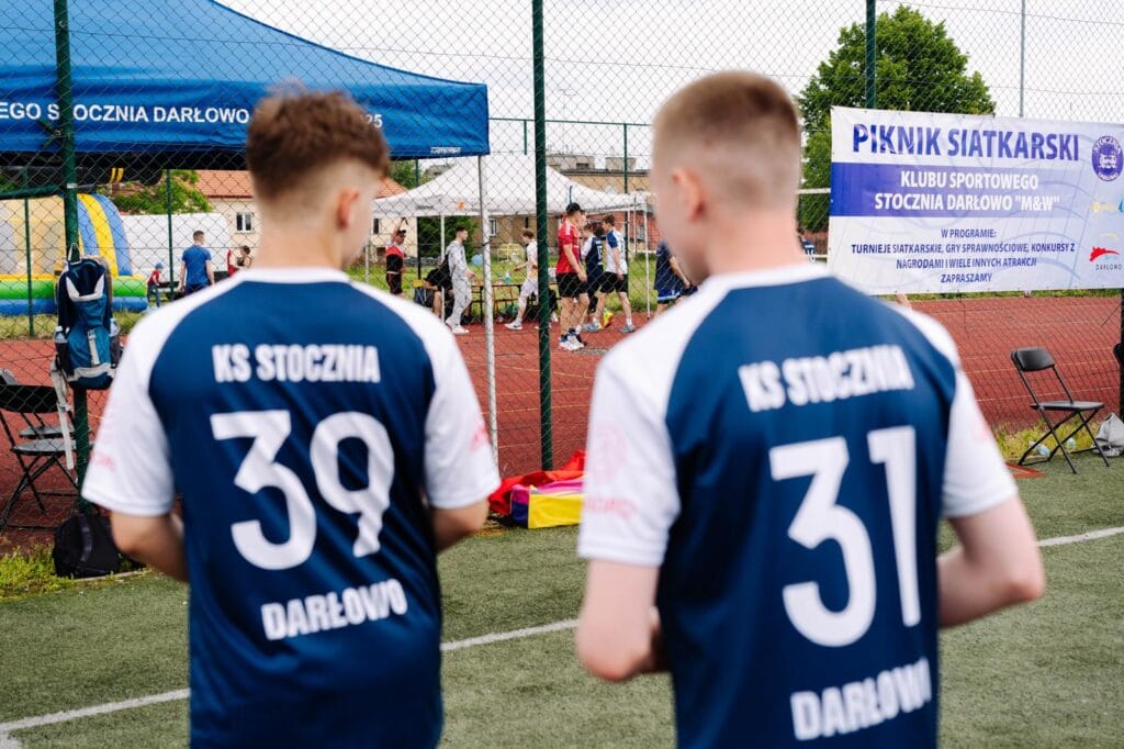 Mężczyźni obserwujący turniej siatkówki na zewnątrz