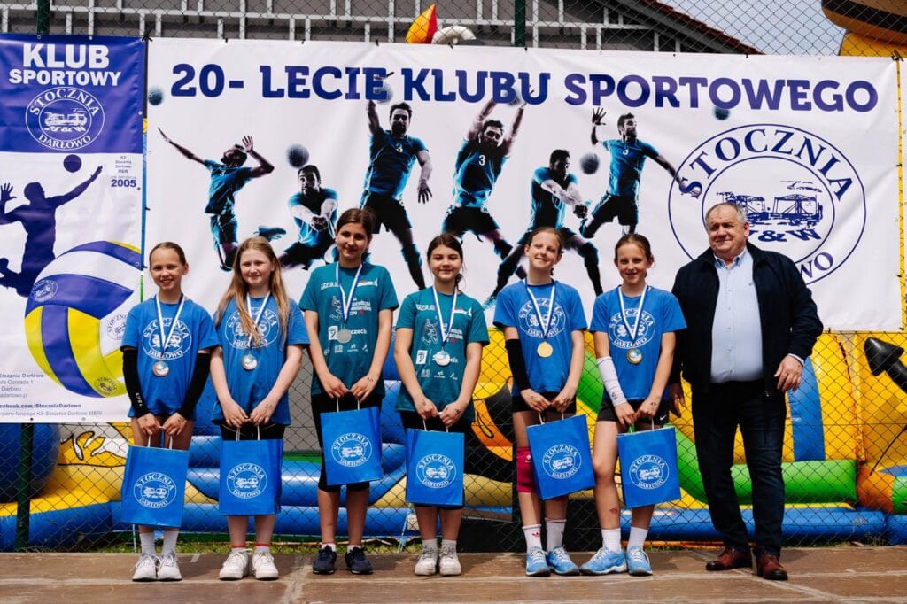 Dziewczęta z medalami przy bannerze klubu sportowego